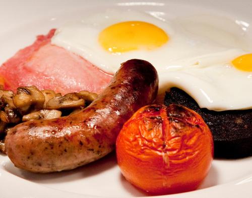 a plate of breakfast food with eggs sausage and tomatoes at The Charles Bathurst Inn in Richmond