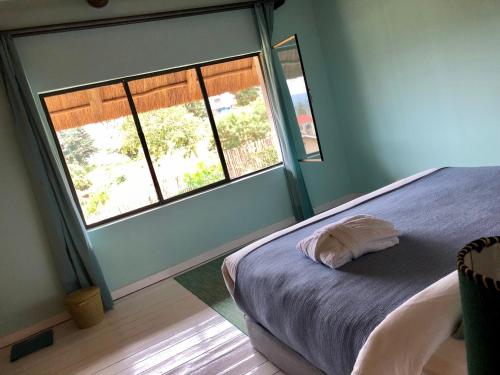 a bedroom with a bed and two windows at Pili Pili Boutique Hotel in Kigali