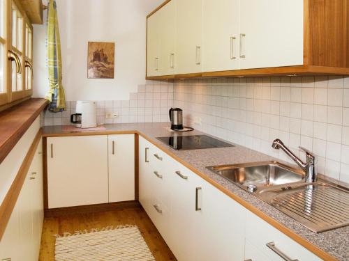 una cocina con armarios blancos y fregadero en Plonerhof, en Lagundo