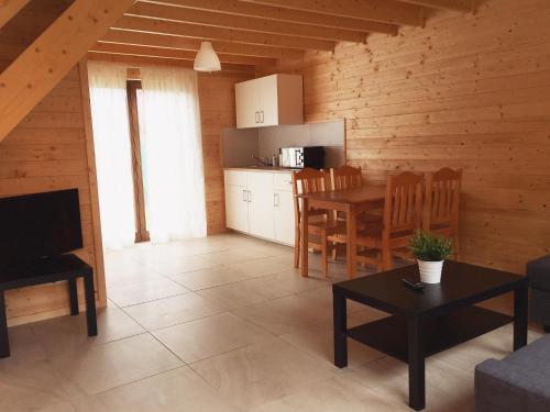 Una sala de estar con una mesa y una cocina. en Ferienhäuser Eurobaltyk, en Rewal