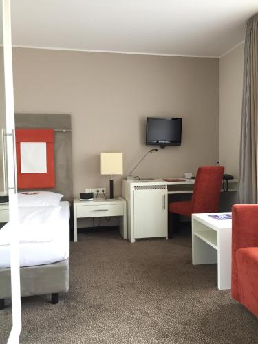 a hotel room with a bed and a desk with a television at Hotel Westfalen Hof in Rahden