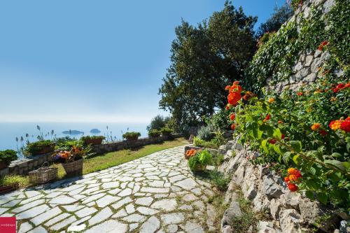 un chemin en pierre avec des fleurs sur un mur dans l'établissement Il Nibbio, à Piano di Sorrento