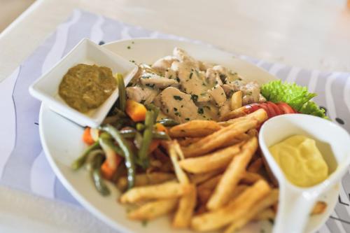 a plate of food with french fries and dips at Pili Pili Boutique Hotel in Kigali