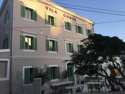 a building with tables and chairs in front of it at Hotel Vila Conte in Veli Lošinj