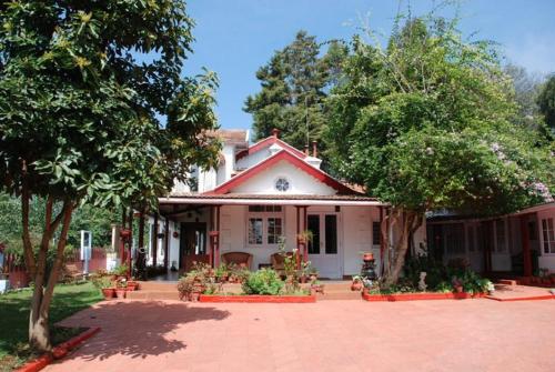 a white house with trees and a brick driveway at Colonial 4 B/R Home, Great for Families, Coonoor in Coonoor