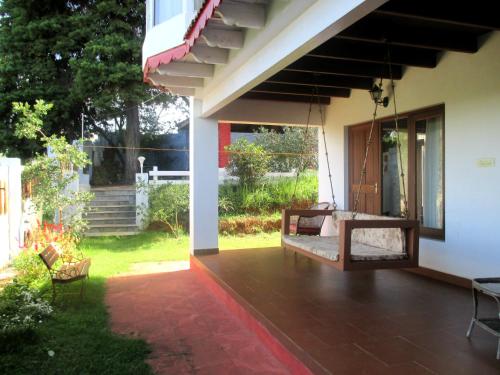 a porch of a house with a porch swing at Colonial 4 B/R Home, Great for Families, Coonoor in Coonoor