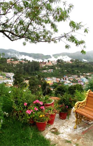 a bench sitting on top of a hill with flowers at Colonial 4 B/R Home, Great for Families, Coonoor in Coonoor