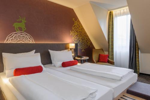 two beds in a hotel room with red pillows at Mercure München City Center in Munich