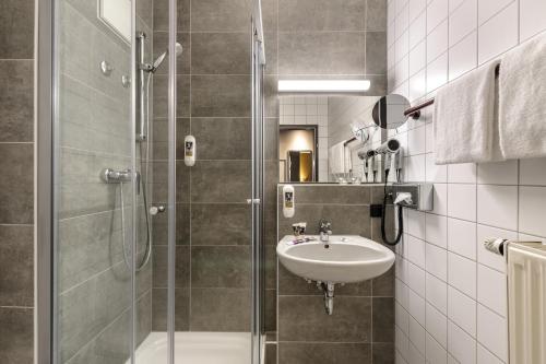 a bathroom with a sink and a glass shower at Mercure Stuttgart Zuffenhausen in Stuttgart