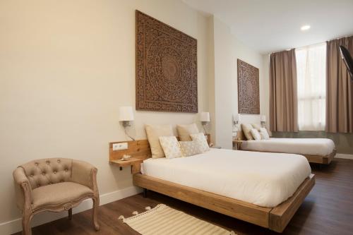 a bedroom with two beds and a chair at Hotel Radha in Hospitalet de Llobregat