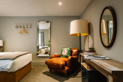 a bedroom with a bed and a chair and a mirror at Ginger Peanut in Bampton