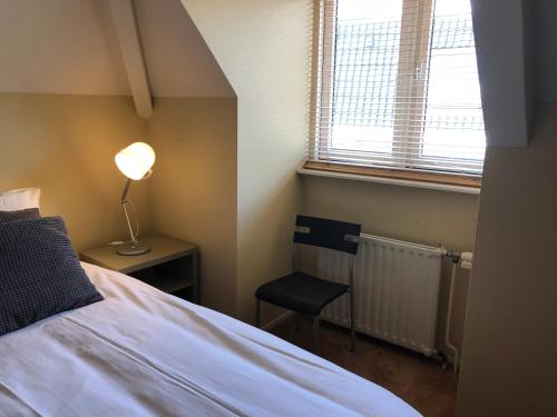 1 dormitorio con 1 cama, 1 silla y 1 ventana en Stadsappartement Ootmarsum, en Ootmarsum