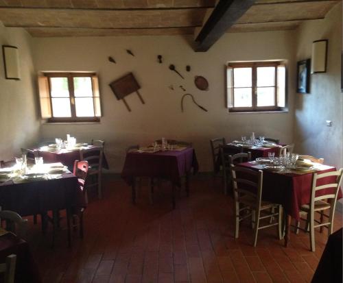 un comedor con mesas, sillas y ventanas en La Tenuta di Castelvecchio, en San Gimignano