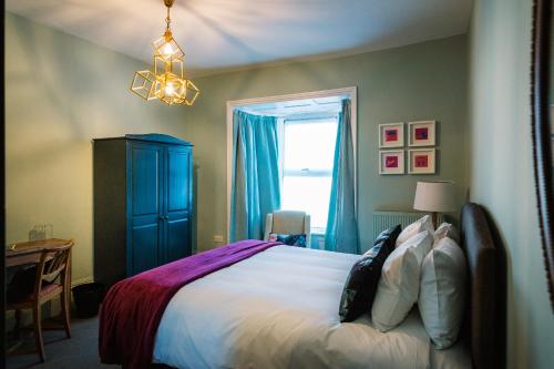 a bedroom with a bed with a blue cabinet and a window at Bampton Townhouse in Bampton