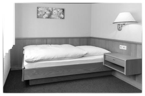 a bed in a bedroom with a lamp and a nightstand at Gasthof Siller in Spiegelberg