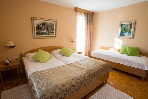 um quarto de hotel com duas camas com almofadas verdes em Penzion Mayer em Bled