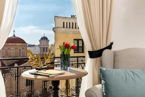 uma mesa com um vaso de flores numa varanda em Athens Mansion Luxury Suites em Atenas