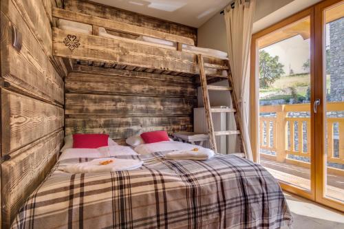 ein Schlafzimmer mit einem Bett mit einer Holzwand in der Unterkunft Apartamenty Smrekowa Lux Zakopane in Zakopane