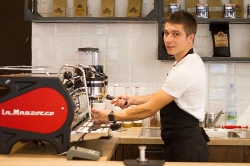 a man in a kitchen preparing food in a machine at Royal Court Legerova in Prague