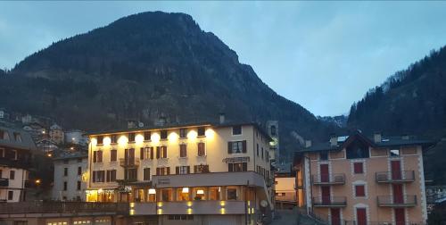 a large building with a mountain in the background at Hotel Pedretti in Branzi