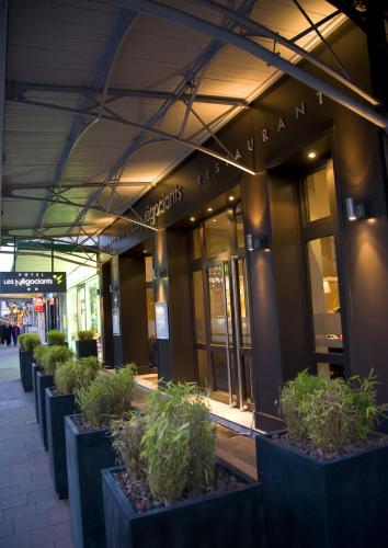 un bâtiment avec des plantes en pot devant dans l'établissement Hotel Les Negociants, à Valence
