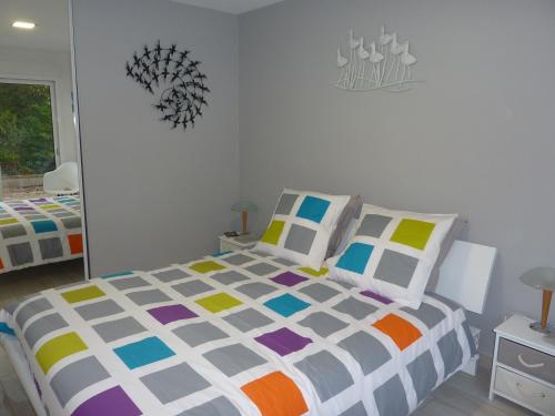 Un dormitorio con una cama con un edredón colorido. en Gites La Baie des Remparts Meublé Les Aigrettes, en Saint-Valery-sur-Somme