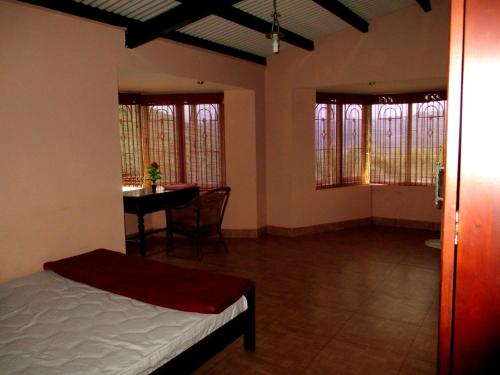 a bedroom with a bed and a table and windows at Relaxing 2 B/R Estate House, Deenaty, Tamil Nadu in Coimbatore