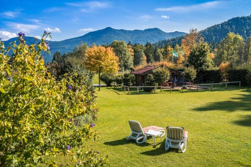 two chairs and a table in a field with mountains at LandererMühle in Lenggries