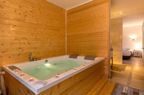 une baignoire jacuzzi dans une chambre avec des murs en bois dans l'établissement The Originals Boutique, Clair Hôtel, Martigues (Inter-Hotel), à Martigues