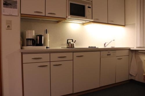 a kitchen with white cabinets and a microwave at Haus Kleemann in Norderney