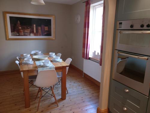 eine Küche mit einem Holztisch mit Stühlen und einem Backofen in der Unterkunft Colegate 4 Bed townhouse in Norwich