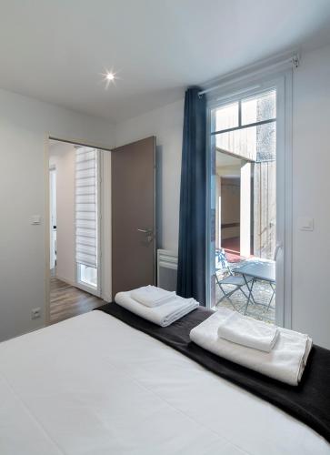 une chambre avec un grand lit blanc avec une fenêtre dans l'établissement Bordo'Appart Hoya Bella, à Arcachon