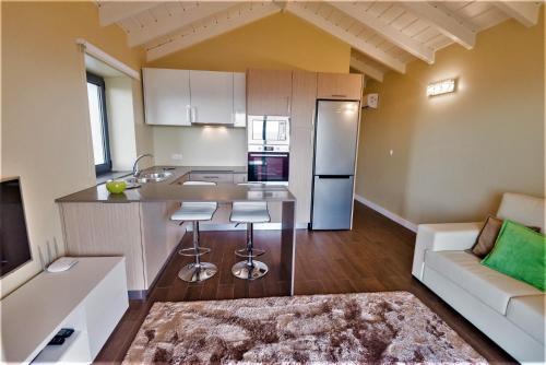 a kitchen with a refrigerator and two stools in a room at Quinta do Basalto in Piedade