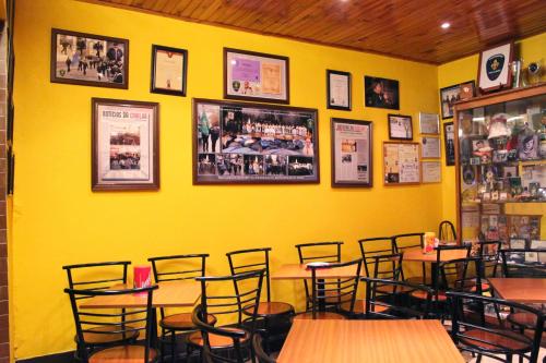 a restaurant with yellow walls and wooden tables and chairs at Mikotania in Covilhã