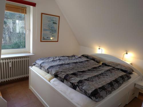ein Schlafzimmer mit einem Bett mit einer Decke darauf in der Unterkunft Whg Suedblick auf Föhr in Goting