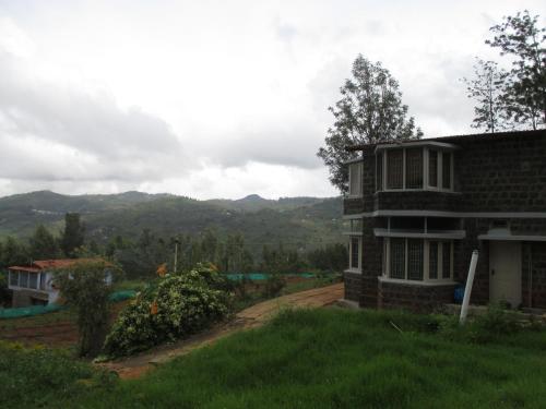 a house on a hill with mountains in the background at Relaxing 2 B/R Estate House, Deenaty, Tamil Nadu in Coimbatore
