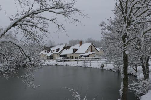 a house covered in snow next to a river at Chambres et Table d'Hôtes Les Machetières in Langeais