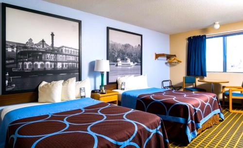a hotel room with two beds and a table at Super 8 by Wyndham Burlington in Burlington