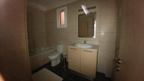 a bathroom with a toilet and a sink and a mirror at Pyla Gardens A102 in Pyla