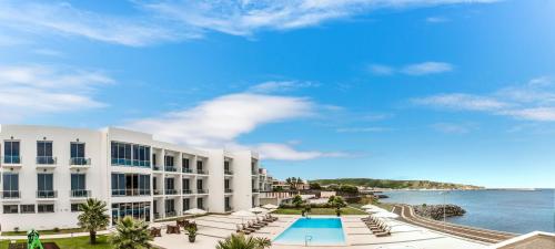 a building with a swimming pool next to the ocean at Atlantida Mar Hotel in Praia da Vitória