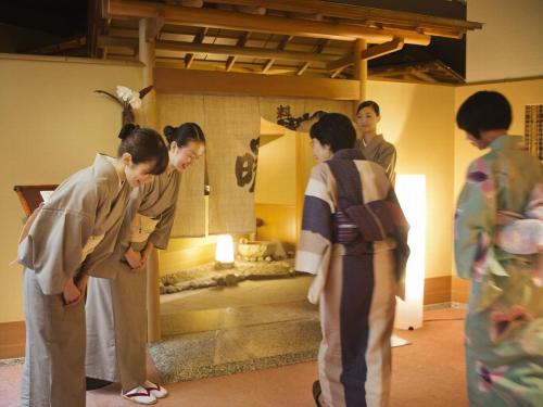 a group of people standing in a room with a fireplace at Honjin Hiranoya Kachoan in Takayama