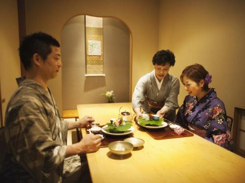 a group of people standing around a table eating food at Honjin Hiranoya Kachoan in Takayama