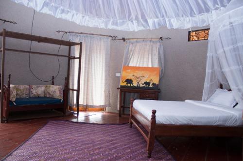 a bedroom with two beds and a canopy bed at Living Waters Resort in Jinja