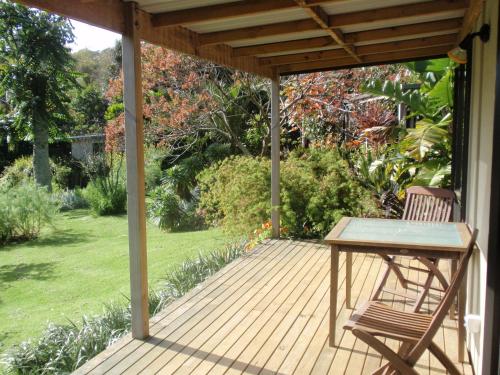 a wooden deck with a table and a chair at Wharepuke Subtropical Accommodation in Kerikeri
