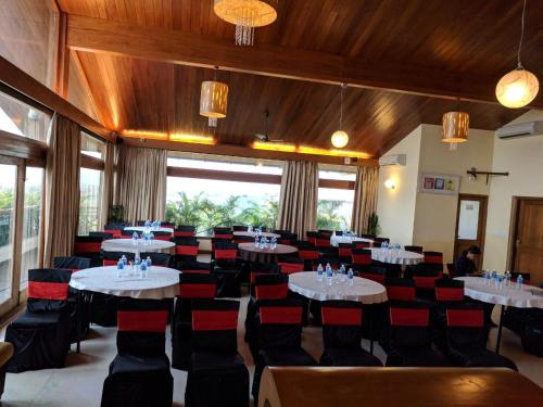 a dining room with tables and red chairs at Varanda Do Mar in Panaji