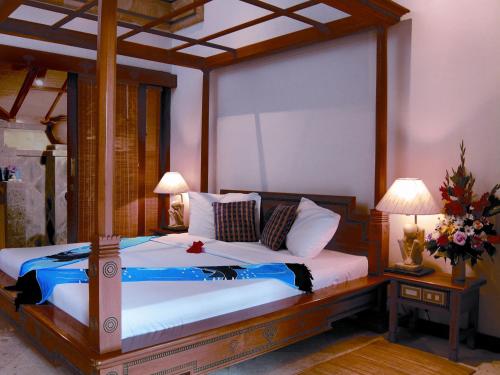 a bedroom with a canopy bed with white sheets and pillows at Puri Bagus Manggis in Candidasa