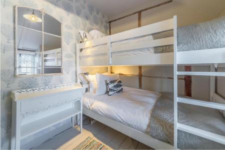 a bedroom with two bunk beds and a mirror at No33 THORNHAM BOUTIQUE COTTAGE 3 in Thornham