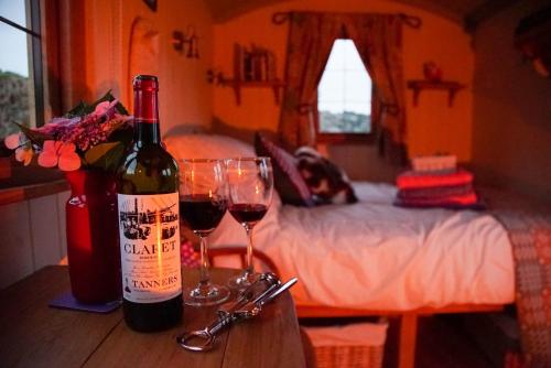 a bottle of wine and two glasses on a table at Storws Y Gorlan Shepherd's Hut in Valley