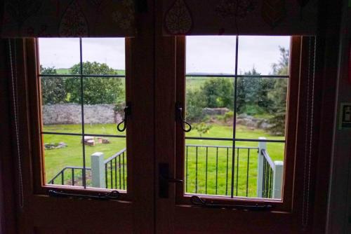 a door with three windows looking out at a yard at Storws Y Gorlan Shepherd's Hut in Valley
