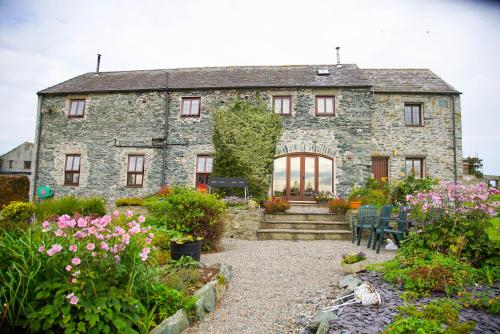 an old stone house with a garden in front of it at Storws Y Gorlan Shepherd's Hut in Valley